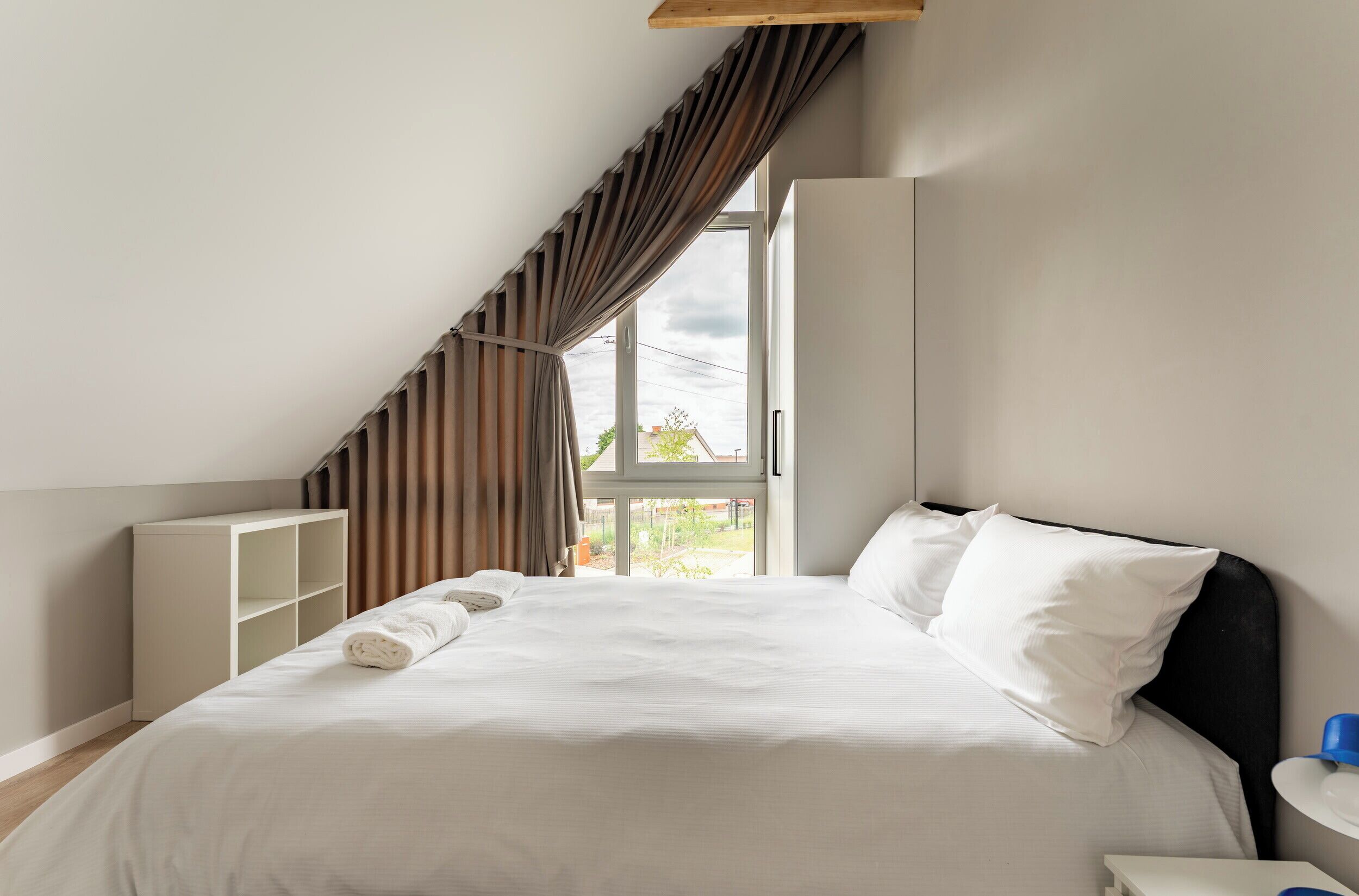 A bedroom with a bed, a window, and a view of the outside.