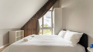 A bedroom with a bed, a window, and a view of the outside.