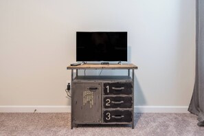 Ein Fernseher auf einem Holzständer mit einer Metall-Aufbewahrungseinheit darunter.
