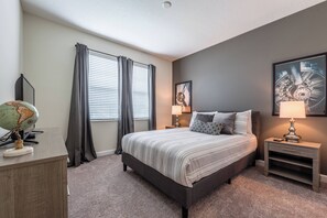 Ein Schlafzimmer mit einem Bett, einem Schreibtisch, einem Globus, Vorhängen und zwei Wandleuchten.