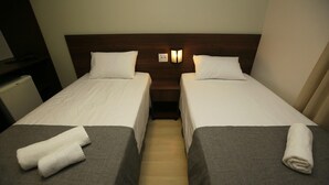 Ein Hotelzimmer mit zwei Einzelbetten, jeweils mit einem Kopfkissen und einem gefalteten Handtuch.