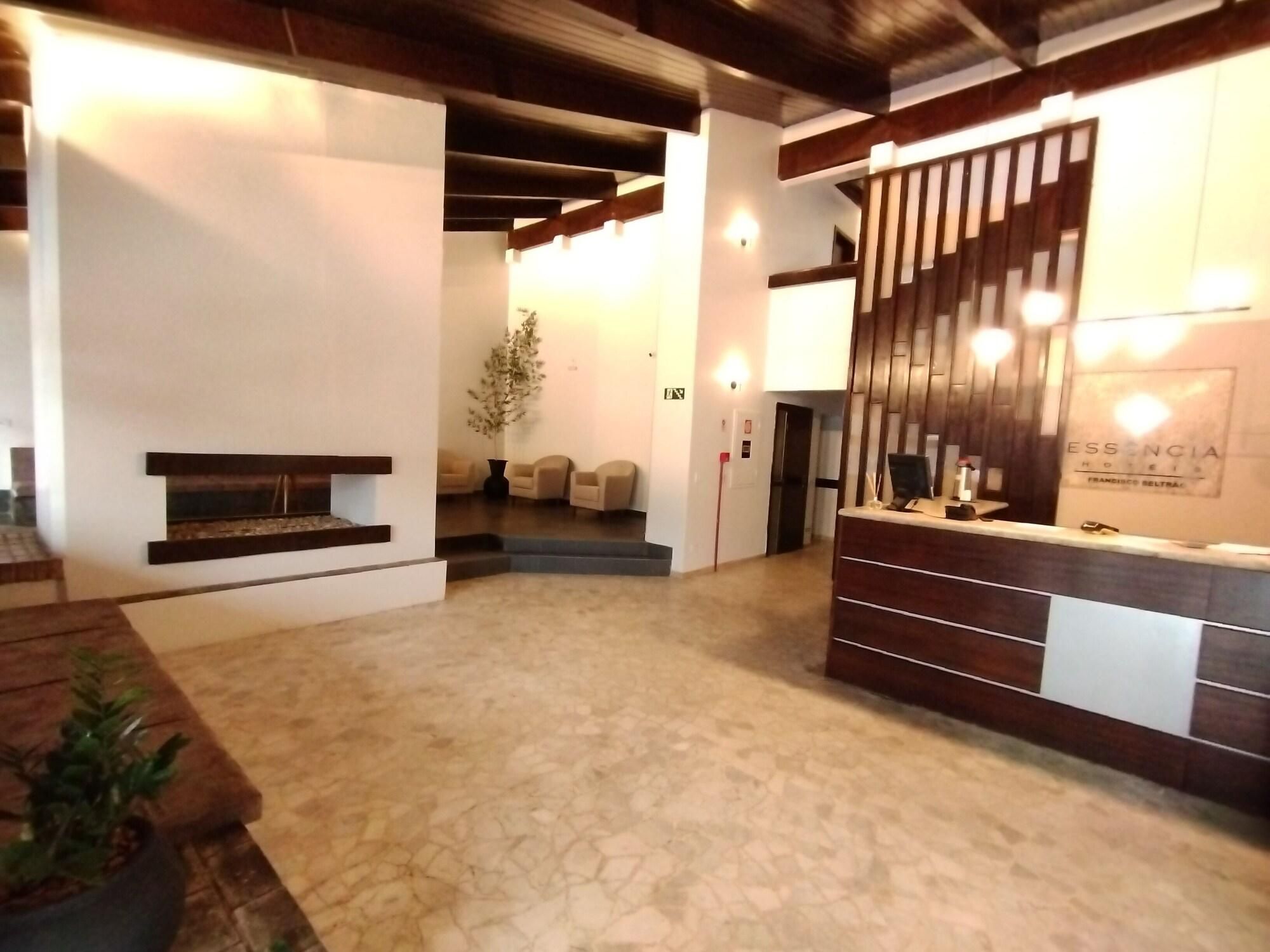 Uma área de recepção de hotel com balcão, espaço para sentar e escadas que levam a outro andar.