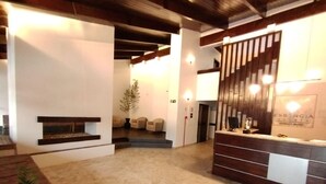 Ein Hotel-Empfangsbereich mit Rezeption, Sitzgelegenheiten und einer Treppe zu einer weiteren Etage.