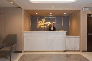 A hotel reception desk with a modern design, a reception area, and a seating area. - The Belamy House (Makati)