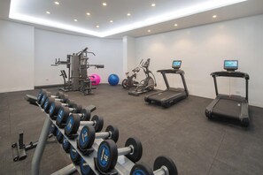 A gym with various exercise equipment including treadmills, an elliptical, and free weights. - The Belamy House (Makati)