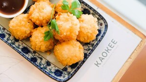 A plate of breaded and fried food items, possibly croquettes, served with a side of sauce.