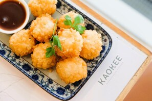 A plate of breaded and fried food items, possibly croquettes, served with a side of sauce.