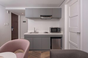 A compact kitchen with a microwave, sink, and built-in oven. - The Belamy House (Makati)