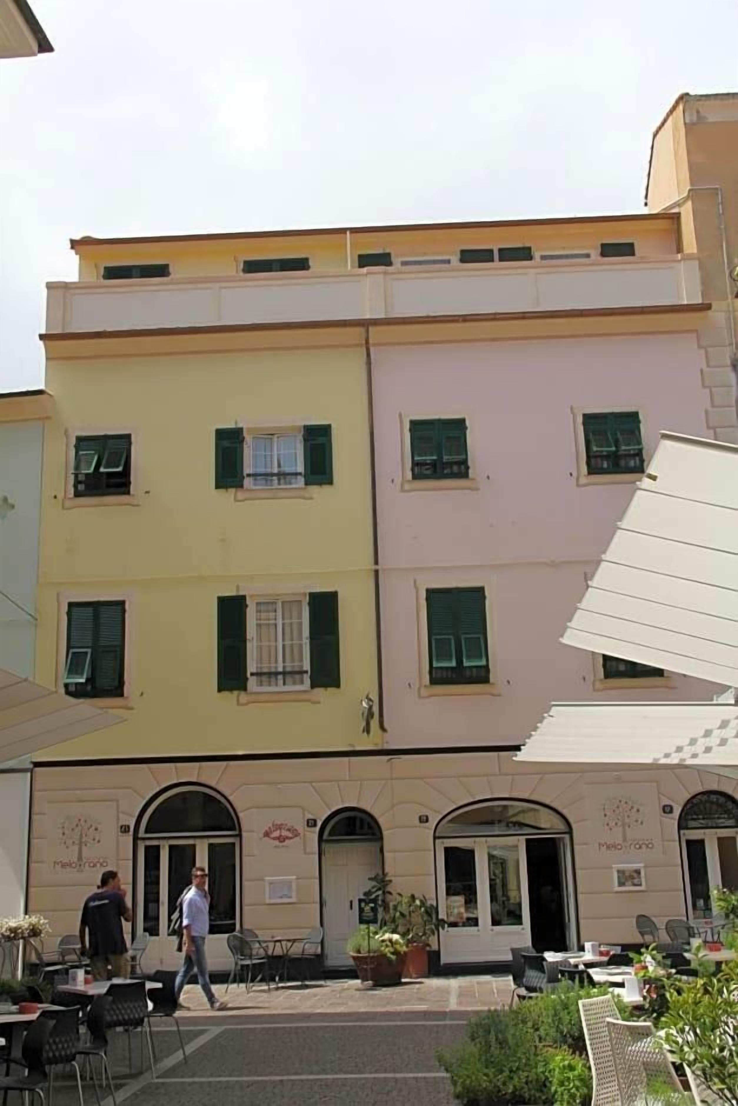 Un edificio con una cafetería y área de mesas al aire libre.
