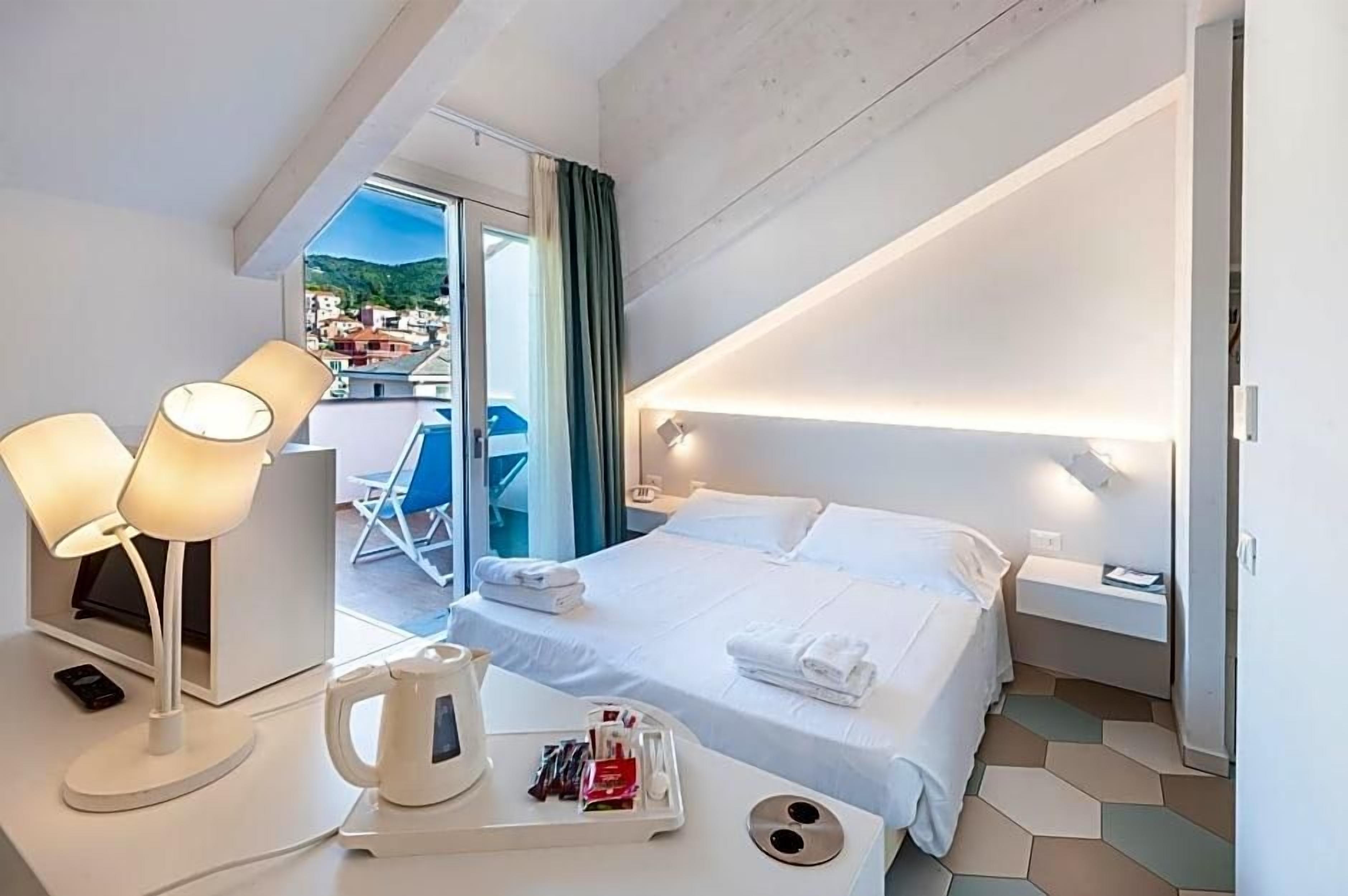 Una camera d'albergo con un letto, un comodino, una lampada e vista sulla città.