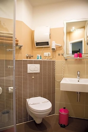 A bathroom with a toilet, sink, and a mirror with a sign above it. - Hotel Sandmanns Am Dom (Cologne)