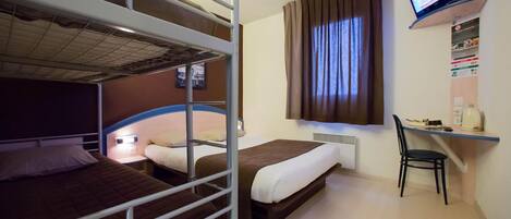A hotel room with bunk beds, a desk, a chair, a television, and a window with curtains.
