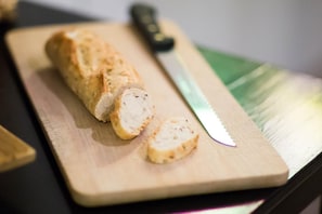 A loaf of bread on a wooden cutting board with a knife beside it. - Hã´tel Akena Nantes (Sainte-Luce-sur-Loire)