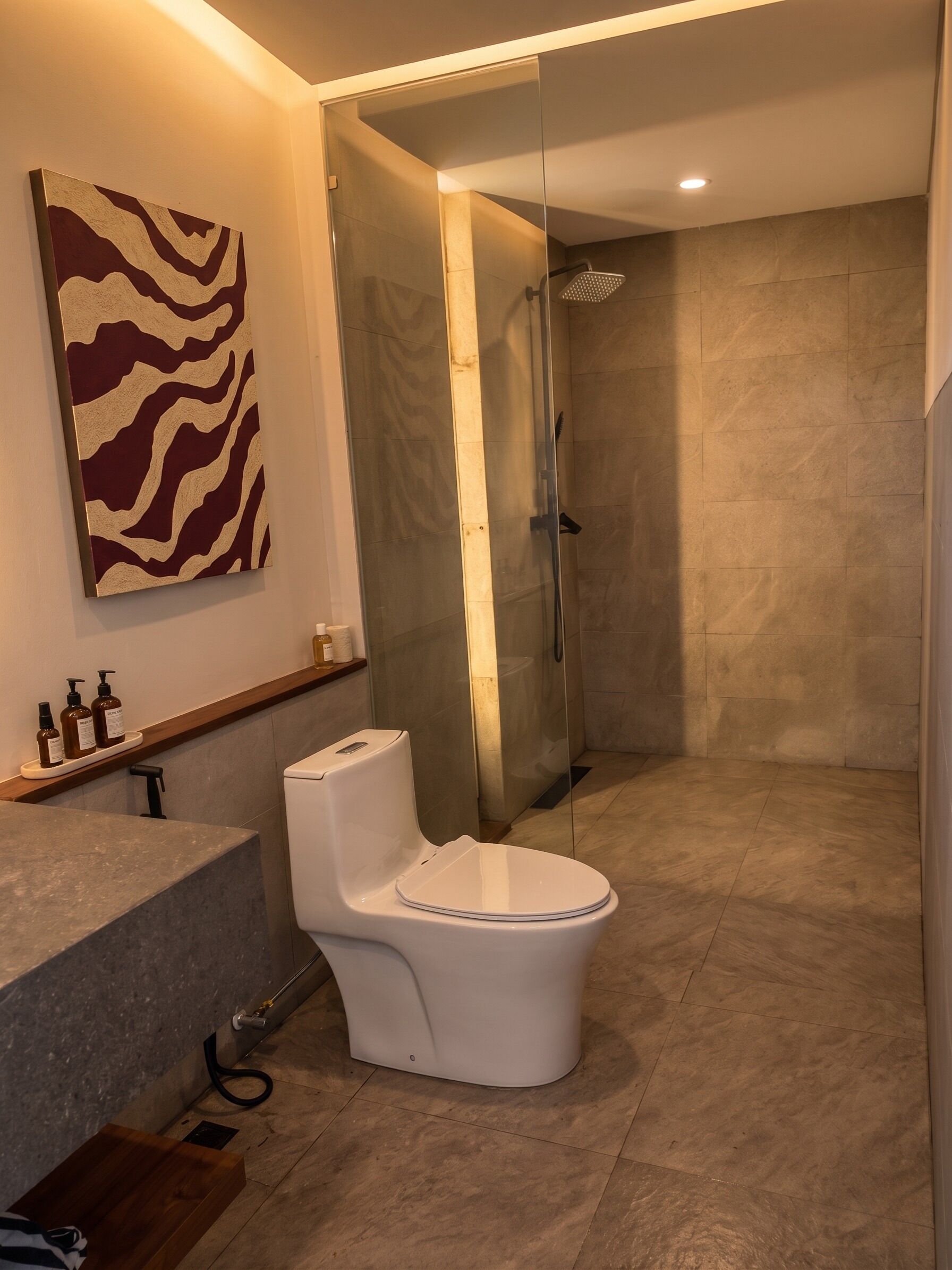 A modern bathroom with a shower, toilet, and a marble floor.