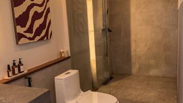 A modern bathroom with a shower, toilet, and a marble floor.