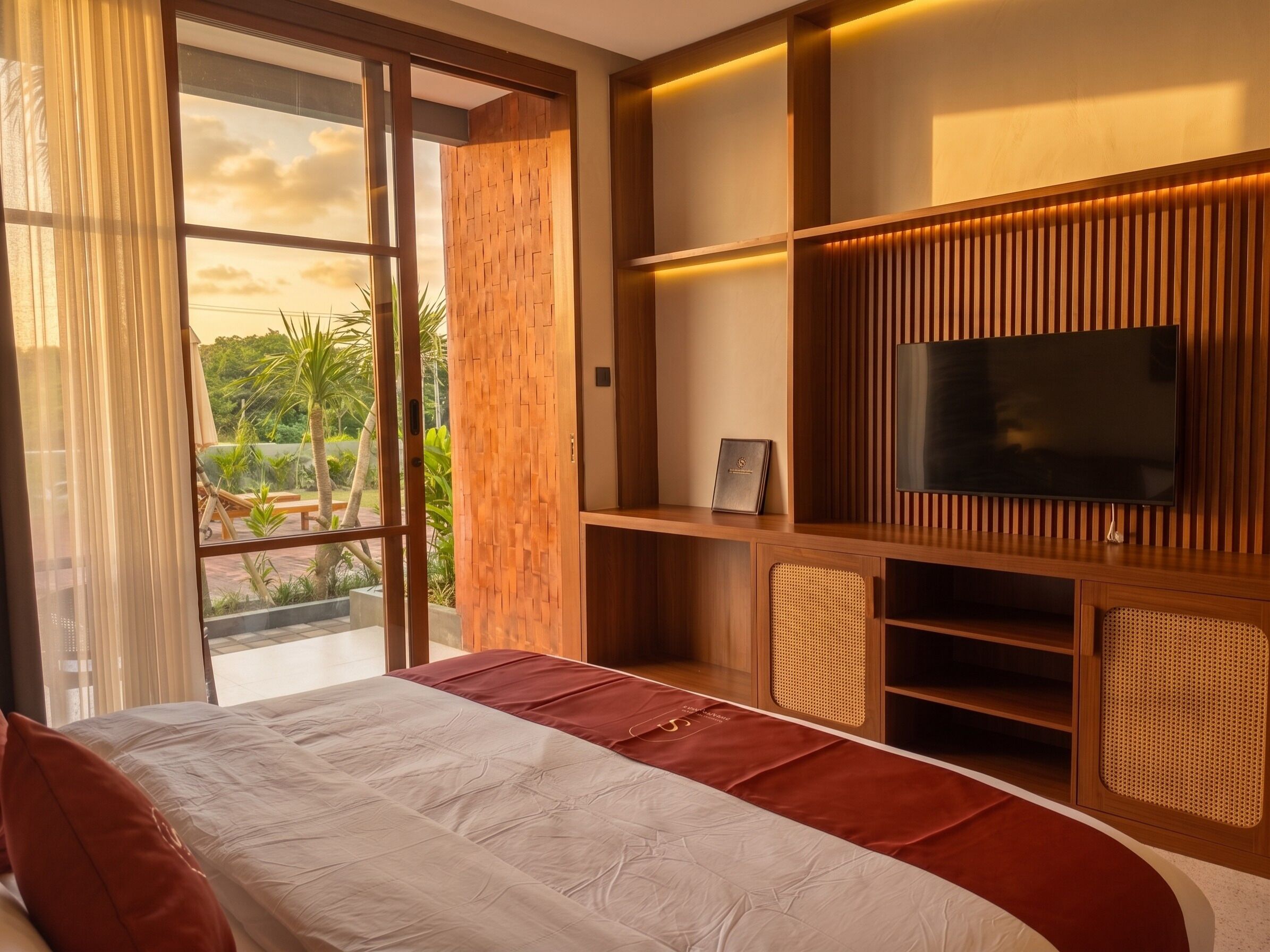 A modern bedroom with a large bed, a television, and a view of a garden.