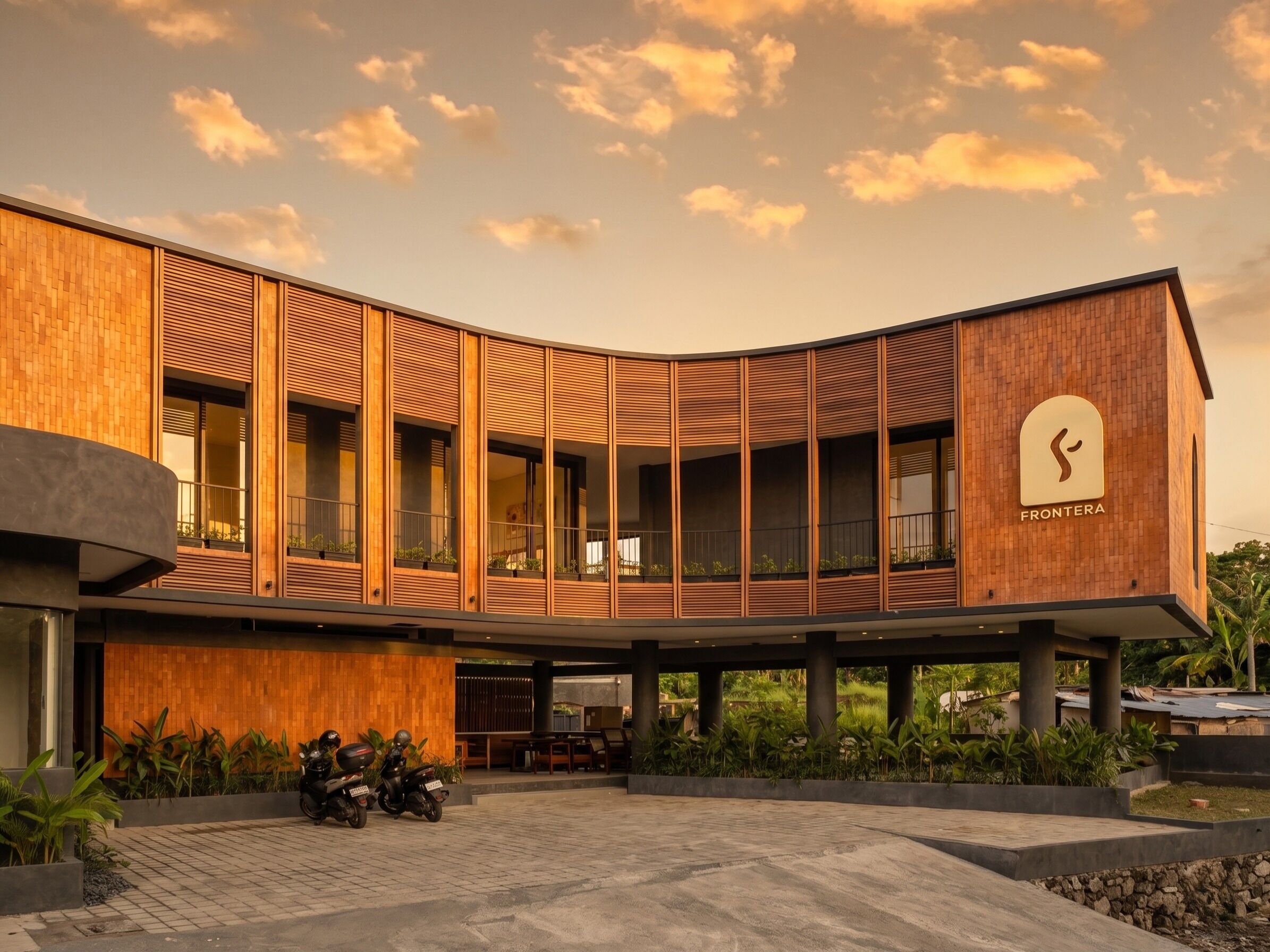 A modern building with a curved facade, large windows, and a sign reading 'FRONTERA'.