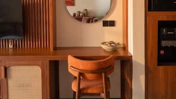 A modern kitchenette with a built-in microwave, a wooden cabinet, and a round mirror above a small table with decorative items.