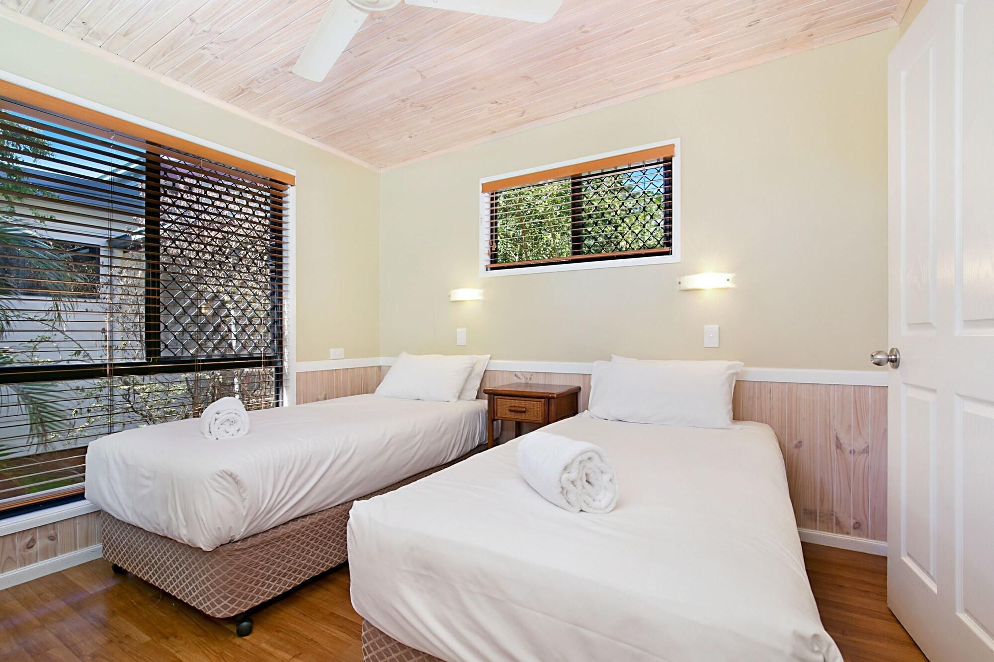 A hotel room with two beds, a window with a view, and a ceiling fan.