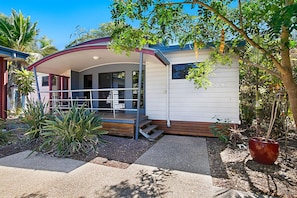A single-story house with a covered porch, a small front yard with plants, and a sign indicating 'Villa 2'.