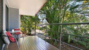 A balcony with a wooden floor, metal railing, and a table with chairs.