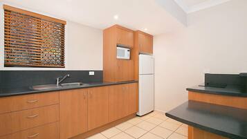A kitchen with wooden cabinets, a stainless steel sink, a microwave, and a refrigerator.