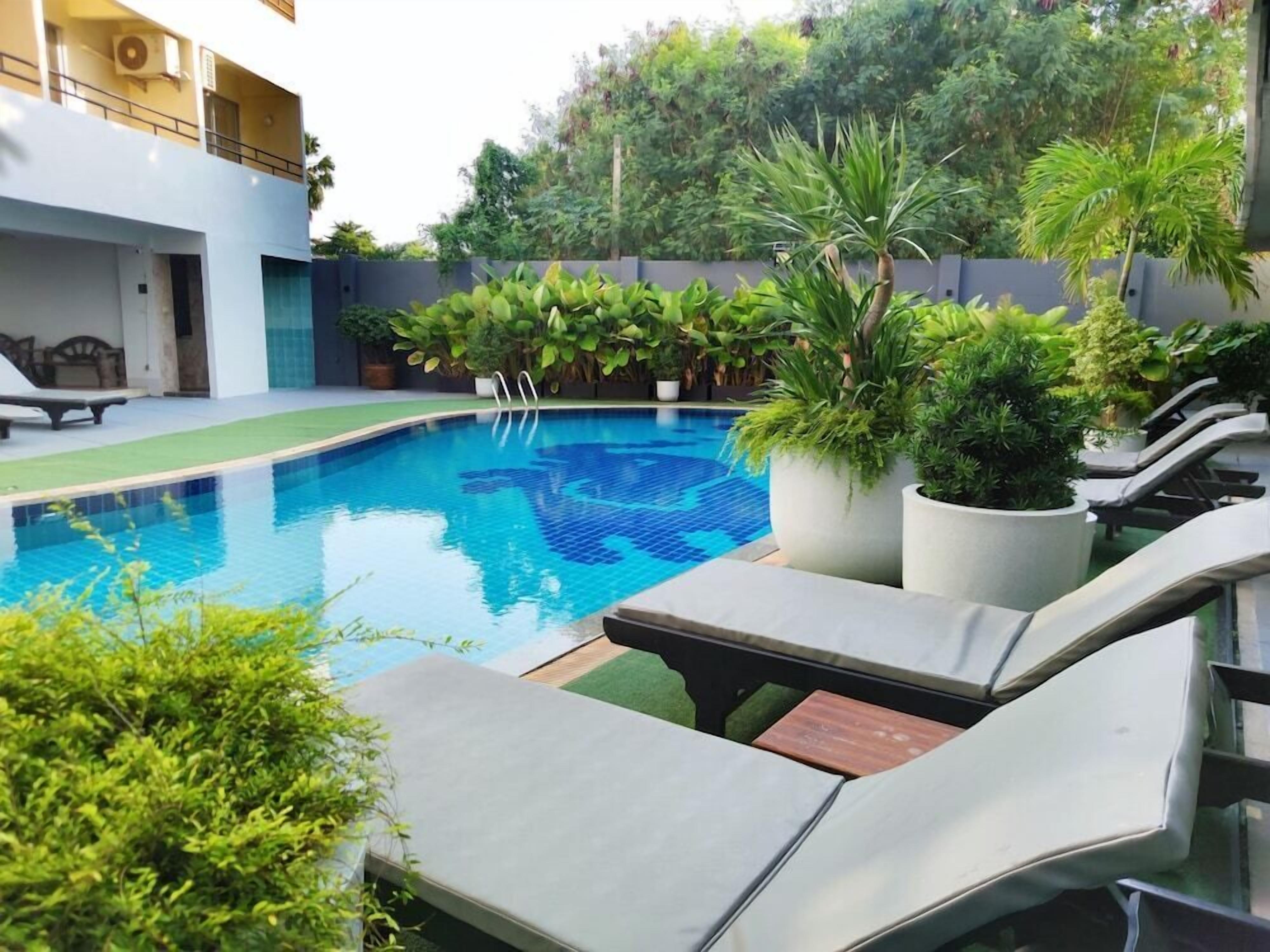 A swimming pool with lounge chairs and potted plants.