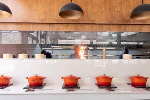 A kitchen with a white countertop, red pots, and overhead lighting. - Justa Rasa Retreat & Spa Rishikesh (Yamkeshwar)