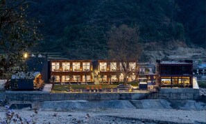 A modern building with multiple levels, large windows, and a well-lit interior. - Justa Rasa Retreat & Spa Rishikesh (Yamkeshwar)