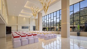 A spacious hall with rows of chairs, large windows, and a chandelier. - Justa Rasa Retreat & Spa Rishikesh (Yamkeshwar)