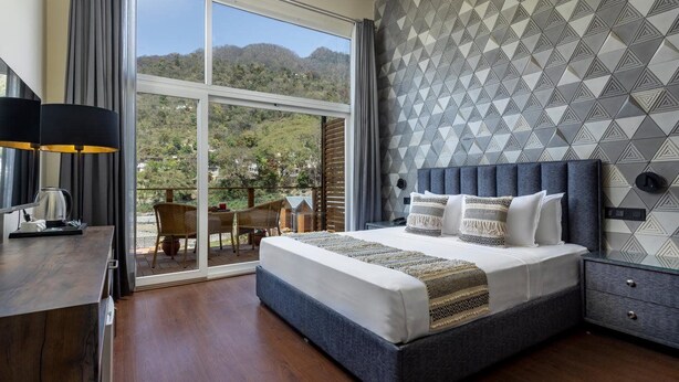 A bedroom with a large bed, a desk, and a view of the outdoors. - Justa Rasa Retreat & Spa Rishikesh (Yamkeshwar)