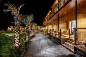 A modern building with a wooden facade, a paved walkway, and outdoor seating areas. - Justa Rasa Retreat & Spa Rishikesh (Yamkeshwar)