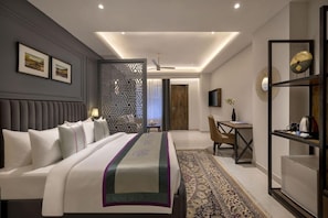 Ein modernes Hotelzimmer mit einem großen Bett, einem Schreibtisch, einem Sessel und einem Fernseher.