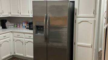 A kitchen with white cabinets, a stainless steel refrigerator, and a coffee maker on the counter.