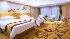 A hotel room with two beds, a sitting area with a chair, a desk, and a decorative wall. - Vienna Hotel (Shanghai)