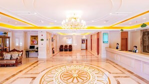 A hotel lobby with a central chandelier, a reception desk, and a patterned floor design. - Vienna Hotel (Shanghai)