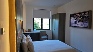 Een slaapkamer met een bed, een bureau en een televisie.