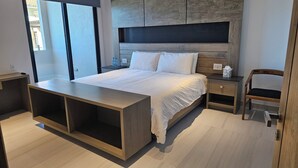 Een moderne slaapkamer met een bed, nachtkastjes, een houten bankje en uitzicht door een raam.