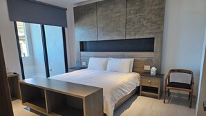 Een moderne slaapkamer met een groot bed, nachtkastjes, een houten bijzettafeltje en een stoel.