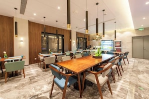 A modern conference room with a long wooden table, multiple chairs, and pendant lighting. - Ssaw Boutique Hotel Cheng Man (Shanghai)
