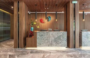 A reception desk with a marble top, wooden paneling on the walls, and a vase with flowers. - Ssaw Boutique Hotel Cheng Man (Shanghai)