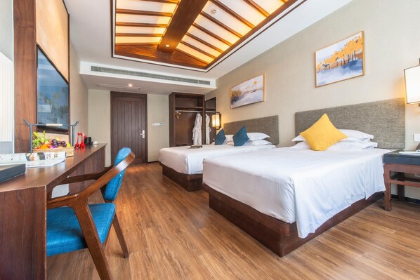 A hotel room with two beds, a desk, a chair, and a wardrobe.