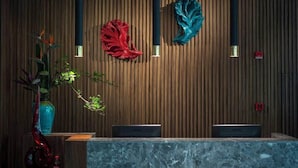 A reception desk with a wooden backdrop, two vertical light fixtures, and a vase with a plant. - Ssaw Boutique Hotel Cheng Man (Shanghai)