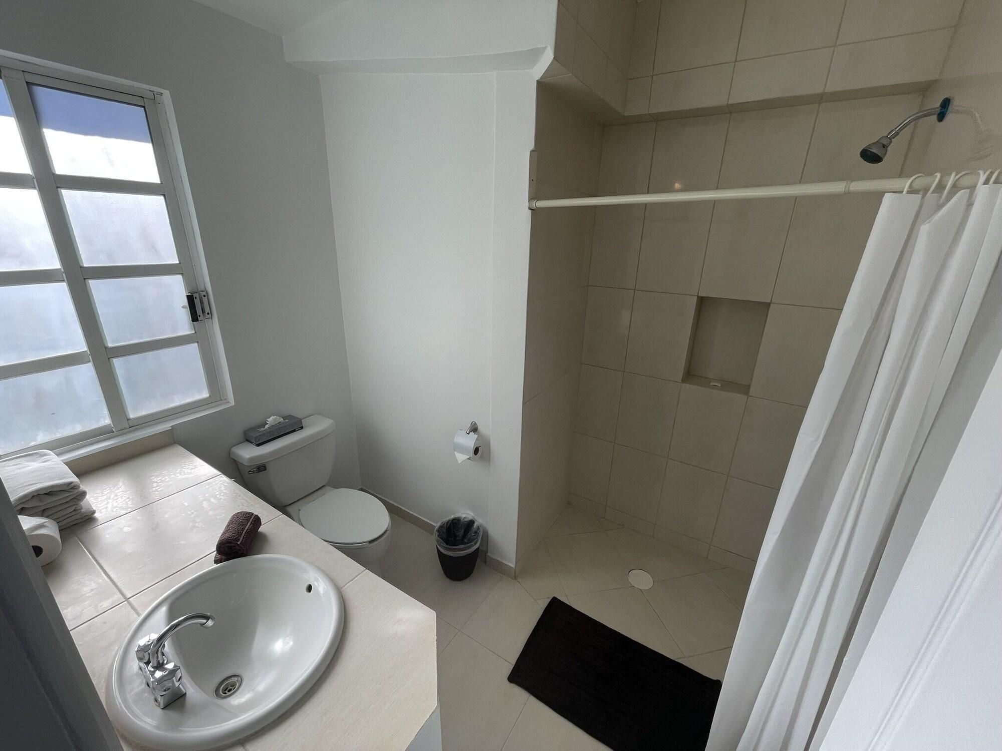 Un baño con inodoro, lavabo, ducha y ventana.