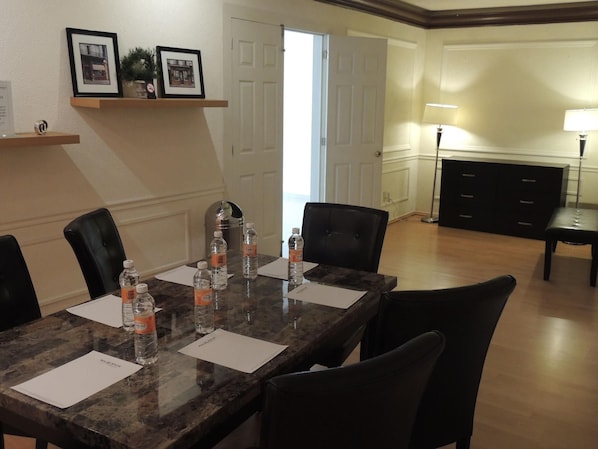 A conference room with a marble table, black chairs, water bottles, and framed pictures on the wall.