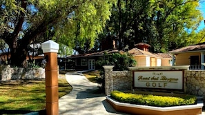 A sign for 'Rent del Bosque Golf' with a pathway leading to a building.
