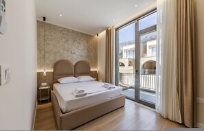A bedroom with a bed, bedside tables, a wall with a textured pattern, and a sliding glass door leading to an outdoor area. - Sapphire Coast Drymades Modern 2BR Apartment (Himarë)