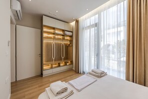 Ein modernes Hotelzimmer mit einem Holzschrank, einem Bett mit ordentlich gefalteten Handtüchern und einem großen Fenster mit Vorhängen.