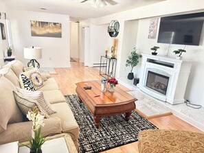 A living room with a sofa, coffee table, fireplace, TV, and decorative items.