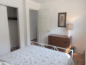 A bedroom with a bed, a dresser, a door, and a lamp.